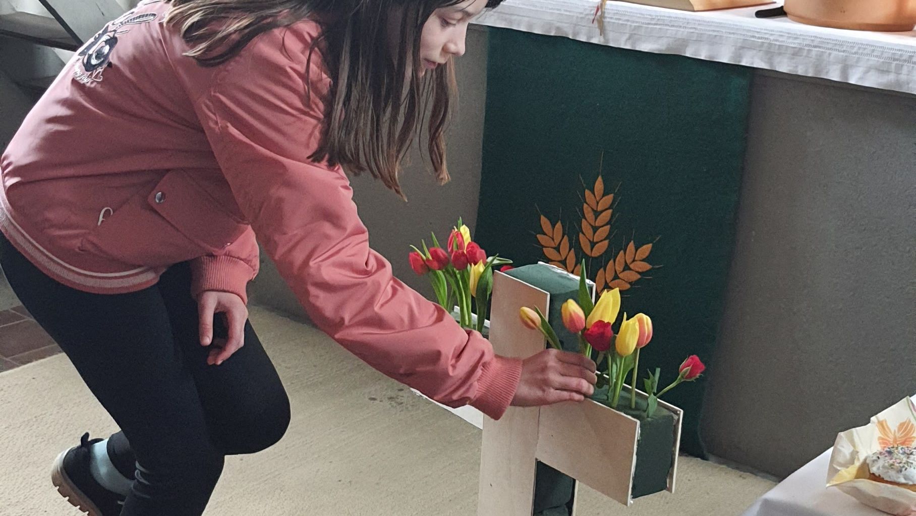 Jugendliche schmückt das Kreuz in einer Kirche